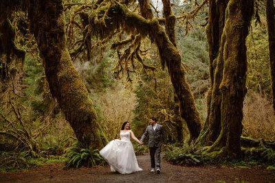 couple in wedding attire with bouquet embraces in front of Olympic Mountain range