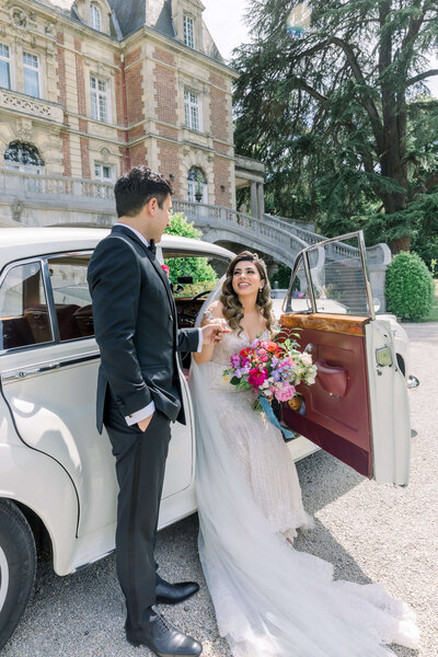 Anokina and Patrick at their wedding in France getting out of a classic car