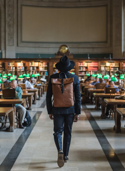 product shot of man showcasing a hand crafted backpack at the boston public library