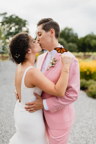 bride kissing with monarch butterfly on finger outside wedding venue upstate new york