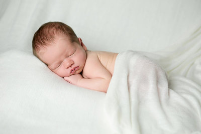 Newborn baby sleeping on pillows at photo session.