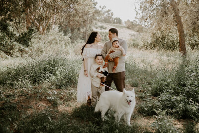 couple posing in field with children and dog