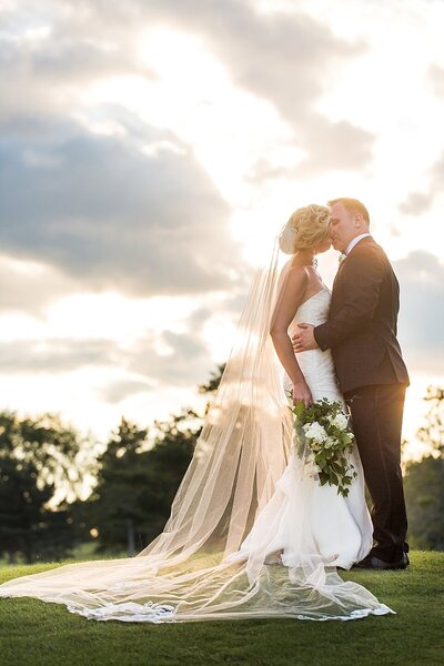 bride and groom kissing in the sunlight