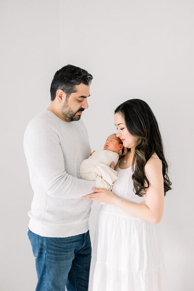 mom and dad holding newborn baby with soft white and neutral color pallette taken by Newborn Photographer Sacramento Kelsey Krall