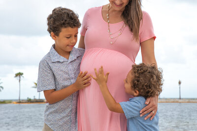 Mother with two sons holding her pregnant stomach