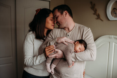 mom and dad snuggling their new baby in her nursery in Fort Collins Colorado
