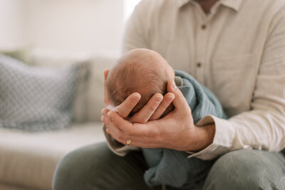 Baby's head in father's hands