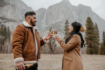 man and woman toast champagne in yosemite valley