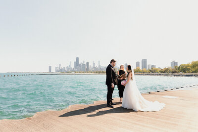 couple getting married on sunny day on Chicago's lakefront with the city skyline in the distance