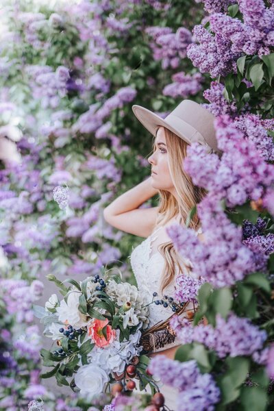 Sacramento Wedding Photographer captures bride wearing hat surrounded by purple blossoms