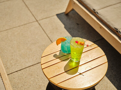 Picture of two brightly colored  drinks on the pool deck next to a sun lounger
