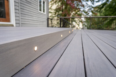 Floor-level view of a gray TimberTech PVC deck with a raised platform with integrated riser lights for safety. 