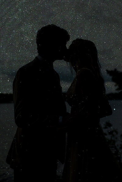 black and white image couple kissing under stars