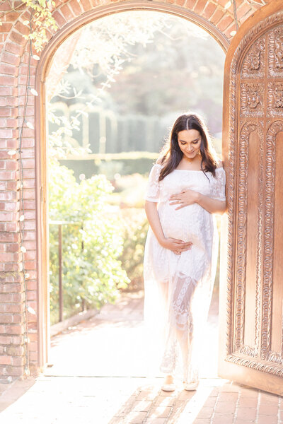 bay area pregnant woman in a white dress standing in a doorway at Filoli