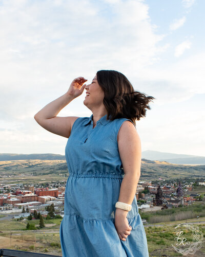 Photo of Ashlyn in a blue denim dress tossing her head and smiling