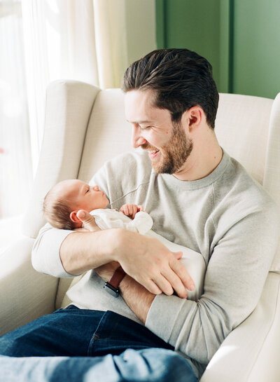 Dad looks lovingly at his newborn baby son during a Raleigh NC newborn session. Photographed by Raleigh newborn photographers A.J. Dunlap Photography.