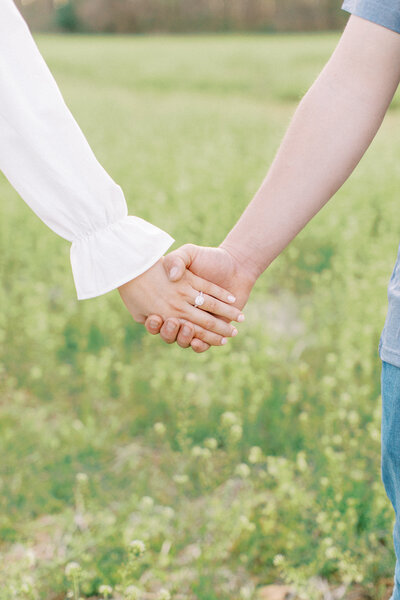 close up of engagement ring holding hands