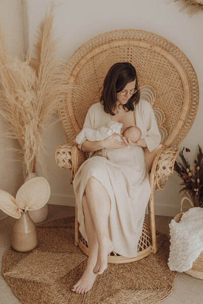 Mama geeft borstvoeding in pauwstoel in bohemien studio