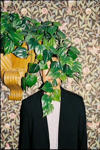 editorial style 35mm film photo of a man with a plant in front of his face at Kissa Tanto Vancouver