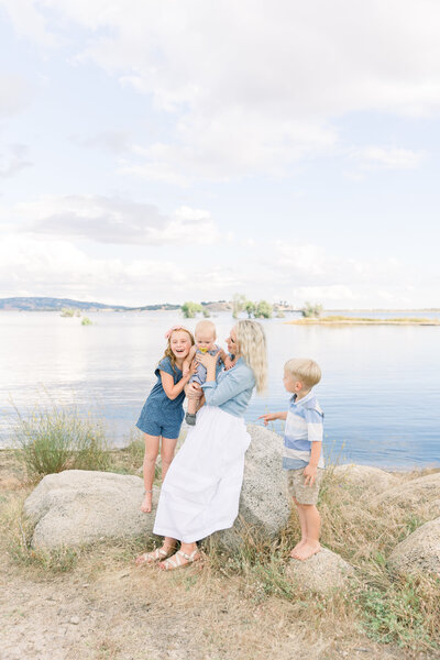 family playin on the rocks together with the lake in the background taken by maternity photographer sacramento Kelsey Krall
