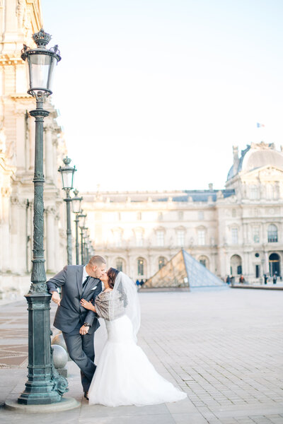 Wedding portrait of a couple at the Louvre in Paris, France leaning on a light post by destination Wedding photographer Angelika Krug Photo & film