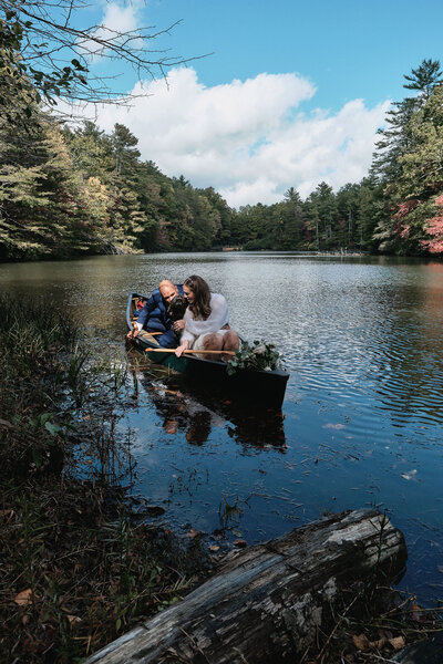 Eloping couple pets their dog while in a canoe together
