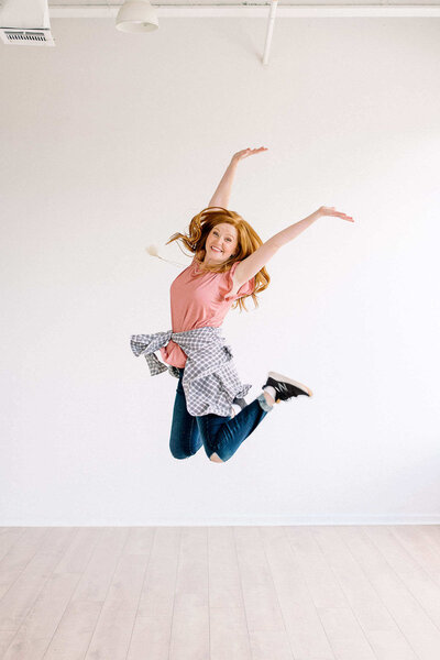 Custom branding and web designer jumping for joy in Dallas Texas studio