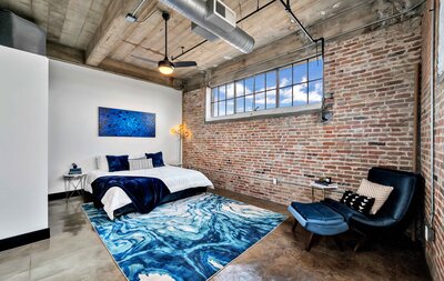 Master bedroom with exposed brick and urban fixtures in this one-bedroom, one-bathroom condo in the historic Behrens building in downtown Waco, TX