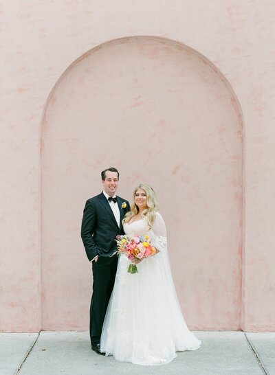 Bride and Groom Smiling at Camera in Front of Pink Wall at The Olde Pink House Photo