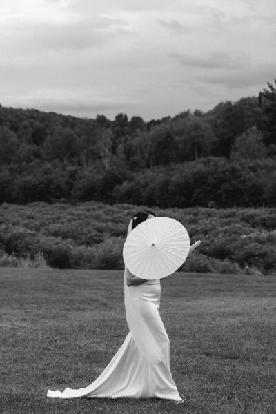 Bride with parasol in monochrome, posing for a snapshot.