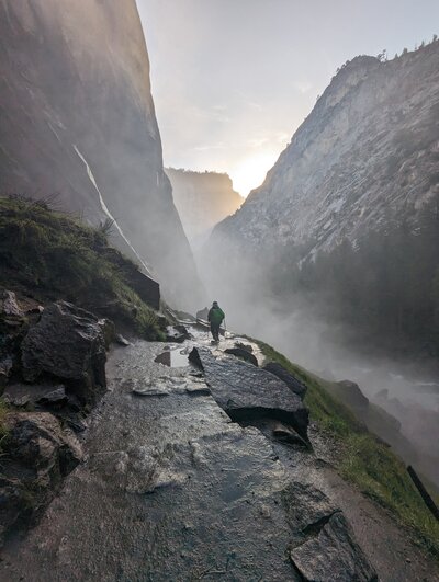 Person hiking through mist from a waterfall
