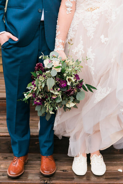 Close up Photo of Bride and grooms shows with her purple and greenery bouquet
