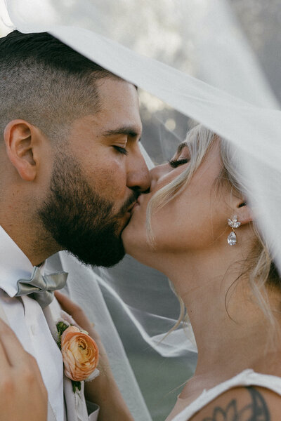bride and groom kissing under veil elopement