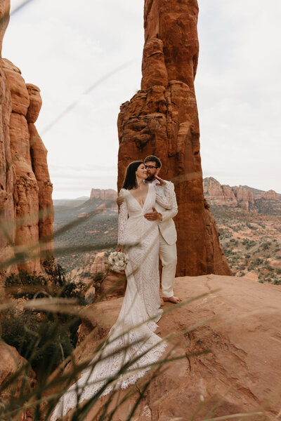 bride and groom embracing on red rocks