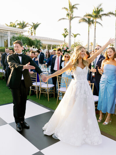 Bride and groom entering their reception on a black and white checkered dance floor at the Resort at Longboat Key Club, photographed by Florida wedding photographer Jake Ford.