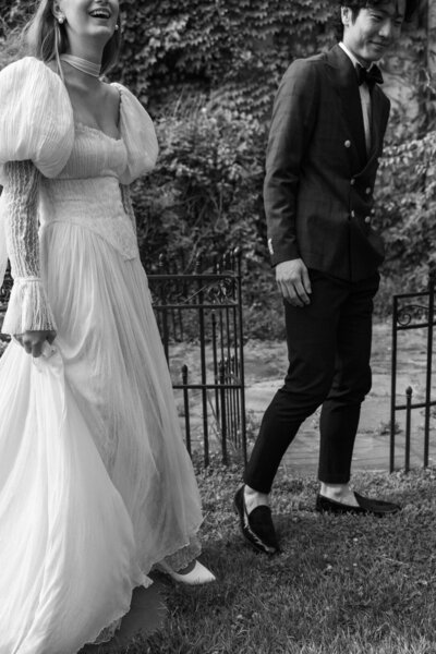 Close up of wedding couple holding hands at ceremony with bride in long-sleeved lace gown and groom in blue houndstooth suit.