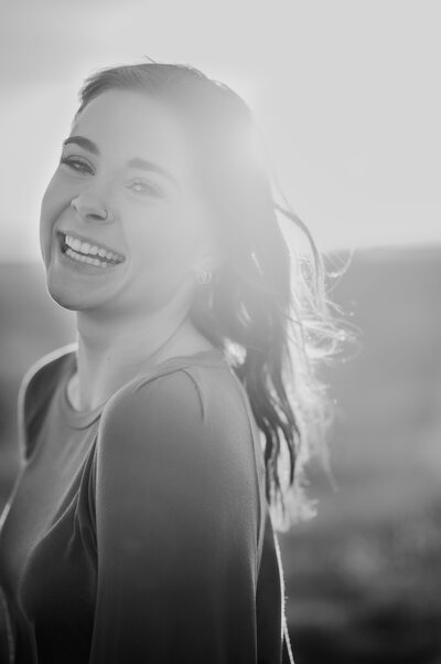Senior girl laughs over her shoulder in sun-drenched black and white image
