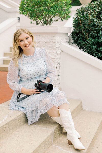 Jessica Greene, a Jackson, MS Wedding Photographer, poses with her camera on the steps of the Crawford House Venue.