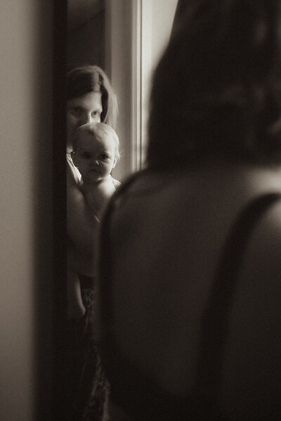 photo reflet dans le miroir maman qui tient son bebe dans les bras noir et blanc