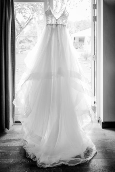 BW photo of a wedding dress  hanging in the doorway before a garden wedding in september in Heerle