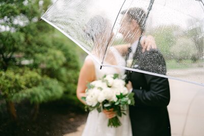 Bride and Groom out of focus with a rainy umbrella in the foreground in  South Bend, Indiana