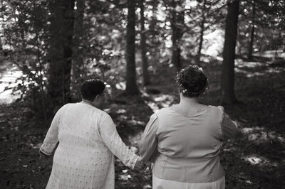 B & W of couple holding hands walking through woods, New England Wedding Planners were vendors