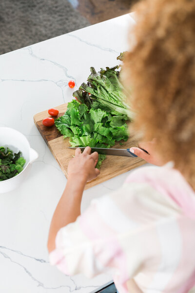 woman cutting healthy vegetables on a cutting board in a bright kitchen