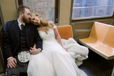bride resting her head on groom's shoulders on nyc subway