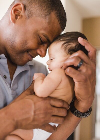 Sweet moment of a father and his newborn baby touching  their heads together.