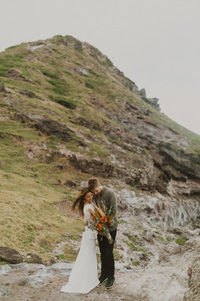 bride and groom standing on rocks embracing