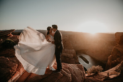bride and groom kissing on top of a mountain