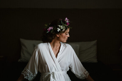 Bride in silk robe and flower crown looking away from camera
