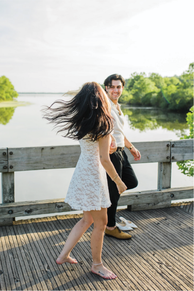Couple in a white dress and button up holding hands walking across a bridge in philadelphia.