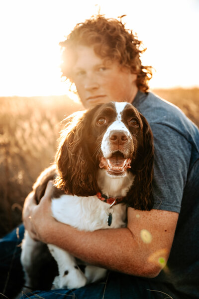 guy senior holds happy dog at Nebraska sunset